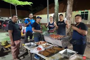 un grupo de hombres parados alrededor de una barbacoa en Marang Village Resort, en Marang