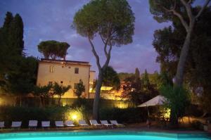 a pool with chairs and a building in the background at Borgo Dolciano in Chiusi
