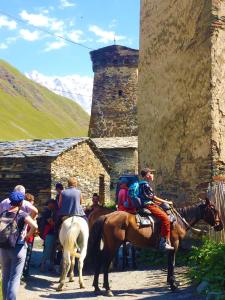 een groep mensen die paardrijden voor een gebouw bij Nizharadze's Tower in Ushguli