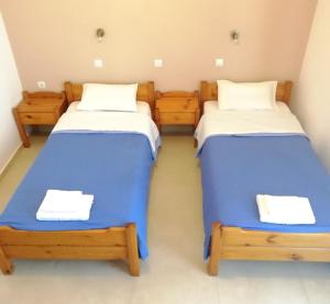 two beds in a room with blue and white sheets at Hotel Thisvi in Stalís