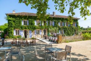 a building with tables and chairs in front of it at Le Moulin in Martres-Tolosane