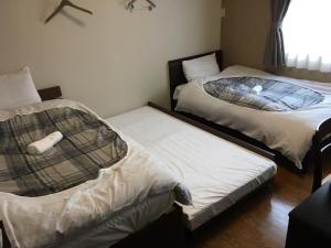 two twin beds in a room with a window at Hostel Mallika in Hiroshima