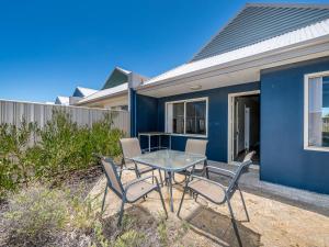 a table and chairs in front of a blue house at Seafront Unit 60 in Jurien Bay