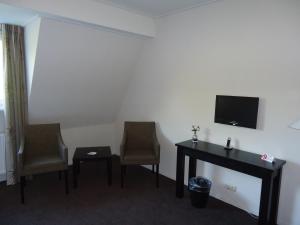 a room with two chairs and a desk and a television at Hotel en Restaurant de Stripe in Wijnjewoude