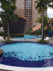 a large swimming pool with palm trees and a building at Times Square Private Service Suite At KL in Kuala Lumpur