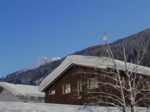 una casa cubierta de nieve con una montaña en el fondo en ARLBERGhome Komfort-Apartments & Privat-Sauna en Wald am Arlberg