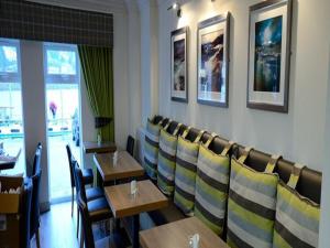 jadalnia z drewnianymi stołami i krzesłami w obiekcie Anchor Hotel and Seabed Restaurant w mieście Tarbert