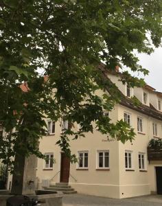 a white building with a tree in front of it at Gästehaus an der Frauenkirche in Günzburg