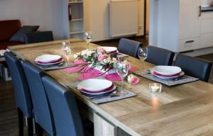 een houten tafel met borden, bloemen en wijnglazen bij Ferienwohnung La Vita in Winterberg