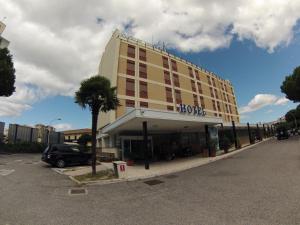 un edificio de hotel con una palmera en un aparcamiento en Benny Hotel, en Catanzaro