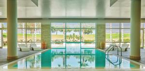 a pool in a building with chairs and windows at Capovaticano Resort Thalasso Spa in Capo Vaticano