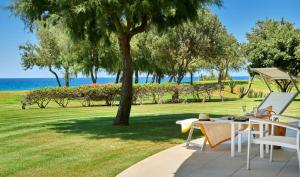 a patio with a table and chairs and the ocean at Capovaticano Resort Thalasso Spa in Capo Vaticano
