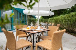 a table with chairs and an umbrella on a patio at Victory Gästehaus Therme Erding in Erding