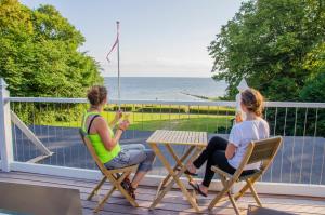 尼斯泰茲的住宿－Østersø kystlejligheder，两个女人坐在甲板上的桌子上,看着大海