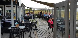 een groep mensen die aan tafels op een dek zitten bij De Zeeuwse Lûûkjes 2 in Baarland