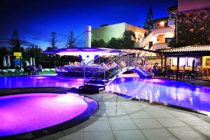 una piscina por la noche con luces moradas en Marigianna Apartments, en Sissi