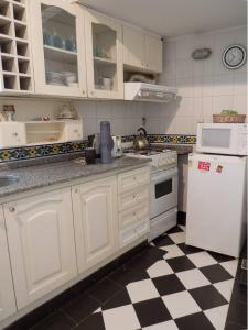 uma cozinha com armários brancos e um piso xadrez preto e branco em Silencioso departamento antiguo em Buenos Aires
