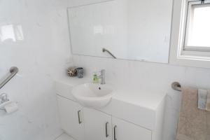 La salle de bains blanche est pourvue d'un lavabo et d'un miroir. dans l'établissement Gawler Townhouse 1 Bedroom, à Gawler