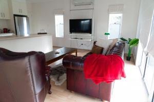 a living room with two leather chairs and a tv at Gawler Townhouse 1 Bedroom in Gawler