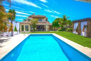 a swimming pool in front of a house at Villa Turrion in Marbella