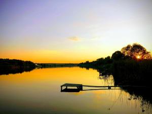 un banco sentado en medio de un lago al atardecer en У Катерини, en Dvozhets