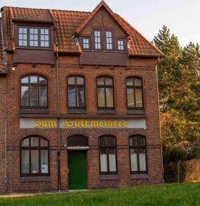 una casa de ladrillo rojo con una puerta verde y ventanas en Sülfmeister Haus, en Lüneburg