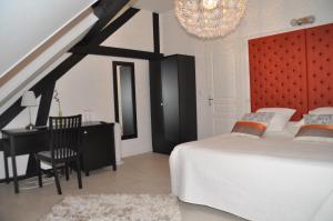 a bedroom with a bed and a desk and a chandelier at L'Atrium in Béthune