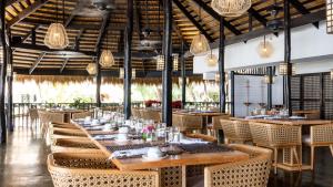 un restaurante con mesas de madera, sillas y luces en El Nido Resorts Miniloc Island en El Nido