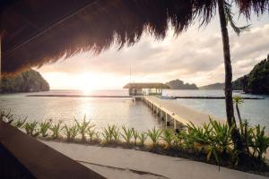 a dock on the water with the sun setting at El Nido Resorts Miniloc Island in El Nido