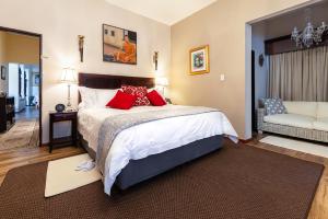 a bedroom with a bed with red pillows and a couch at Amery House in Port Elizabeth
