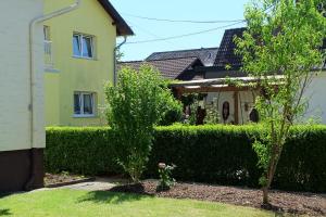 a house with a hedge and two trees in a yard at Ferienwohnung in Dierdorf in Dierdorf