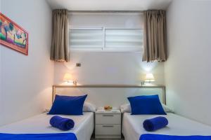 two beds in a room with blue pillows at Alsol Patricio in Playa del Ingles