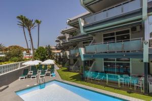 een gebouw met een zwembad en stoelen en parasols bij Alsol Patricio in Playa del Inglés