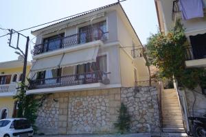 ein gelbes Haus mit Balkonen und einer Steinmauer in der Unterkunft Arkadins in Zakynthos