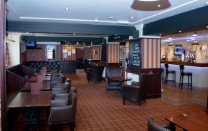 a restaurant with tables and chairs and a bar at Fisher's Hotel in Pitlochry