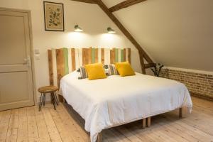 ein Schlafzimmer mit einem großen weißen Bett mit gelben Kissen in der Unterkunft Au Souffle de Vert in Bouvaincourt-sur-Bresle