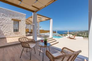 een patio met stoelen en een tafel met uitzicht op de oceaan bij Kallixeni Villas in Rethimnon