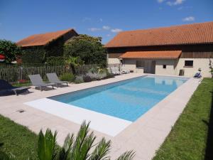 una piscina con 2 sillas y una casa en LA FERME DE ROUFFIGNAC, en Blanzac
