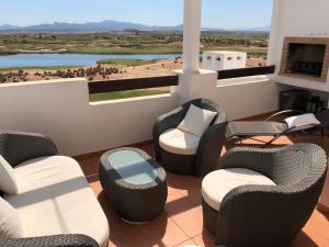 een balkon met rieten stoelen en tafels en uitzicht bij Fairway View Penthouse in Murcia