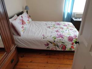 a bed with a floral bedspread and pillows on it at sea view cottage in Bideford