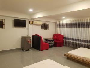 a living room with two red chairs and a tv at Lucky 190 in Chau Doc
