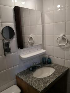 a bathroom with a sink and a mirror and a toilet at Apartamento Solar do Forte - Praia do Forte in Praia do Forte