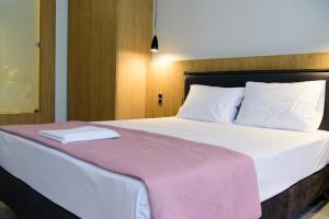 a bed with white sheets and a white comforter at Eva Apartments in Piraeus