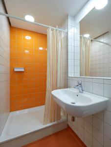 ein Badezimmer mit einem Waschbecken und einem orangefarbenen Duschvorhang in der Unterkunft Youth Hostel Esch/Alzette in Esch-sur-Alzette