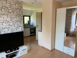 a living room with a tv and a stone wall at Ferienwohnung am Bramschebach in Löhne