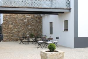 un patio con mesas y sillas y una pared de ladrillo en Casal da Porta - Quinta da Porta, en Mirandela
