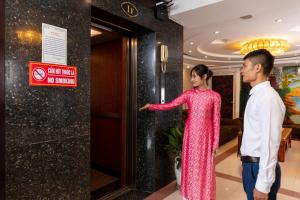 a man and a woman standing next to a door at Hanoi Amore Hotel & Travel in Hanoi