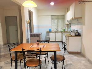 eine Küche mit einem Holztisch und Stühlen im Zimmer in der Unterkunft 6-8pax Cozy Homestay @ Teluk Kemang Port Dickson in Port Dickson
