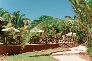a wooden bridge with umbrellas and palm trees at Pousada Aldeia da Serra in Palmas