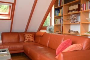 a leather couch in a living room with a book shelf at B&B Kamperfoelie in Gorssel